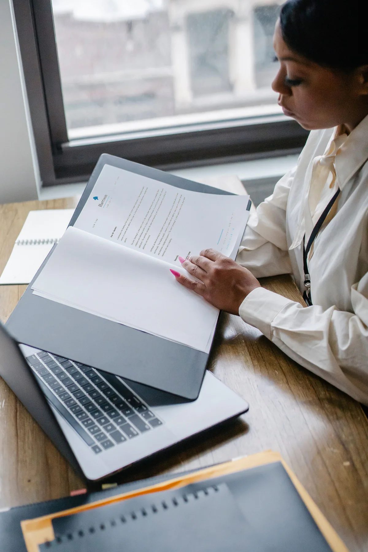 A Black accounting professional reviewing financial documents beside a laptop